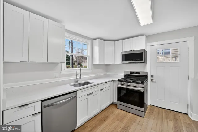 a kitchen with sink a microwave a stove and cabinets