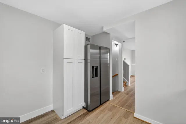 a view of a refrigerator in kitchen and an empty room