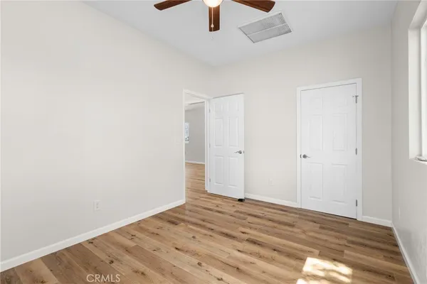 an empty room with a ceiling fan and wooden floor