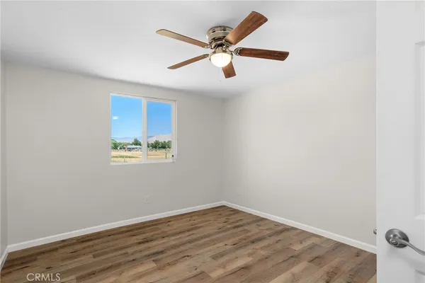 an empty room with wooden floor and ceiling fan