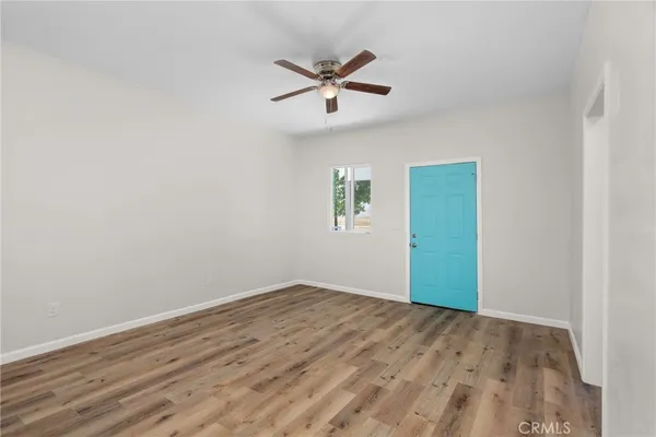 an empty room with wooden floor ceiling fan and windows