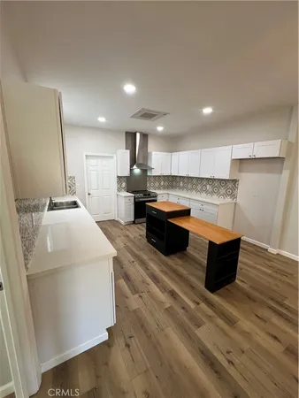a large white kitchen with wooden floors and wooden cabinets