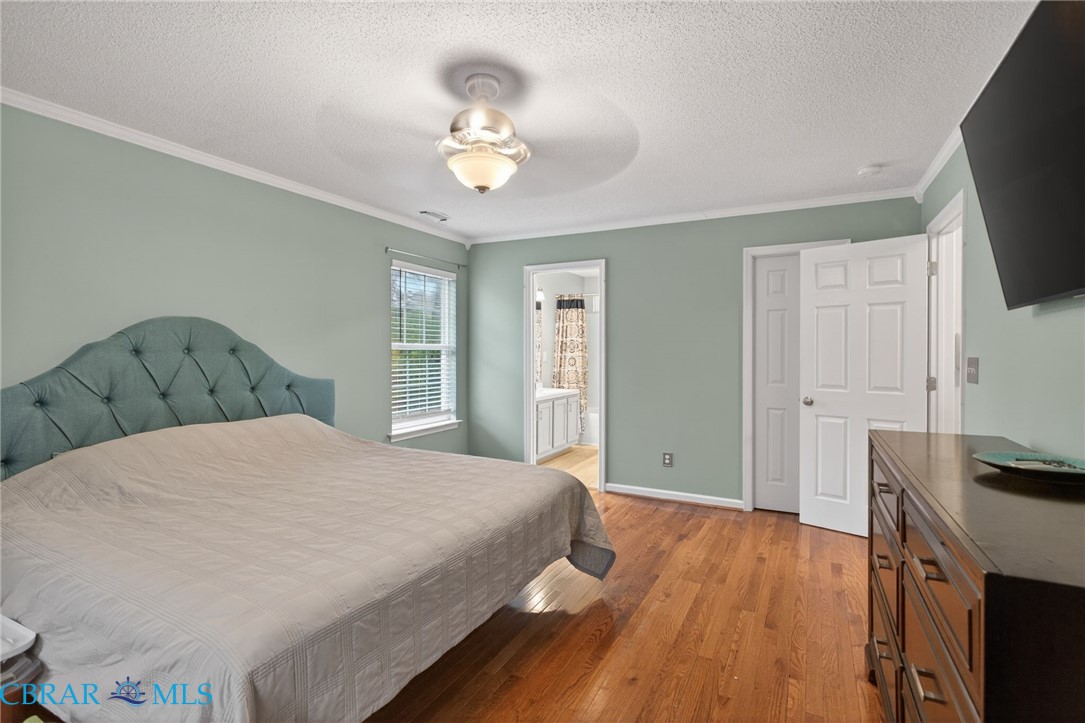 116 Old Field Road Williamsburg, VA 23188 - Photo 20 of 27 Bedroom with light wood-type flooring, crown molding, a textured ceiling, a ceiling fan, and ensuite bathroom