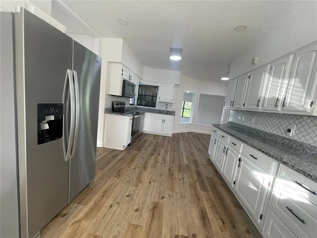 a white kitchen with wooden floor and stainless steel appliances