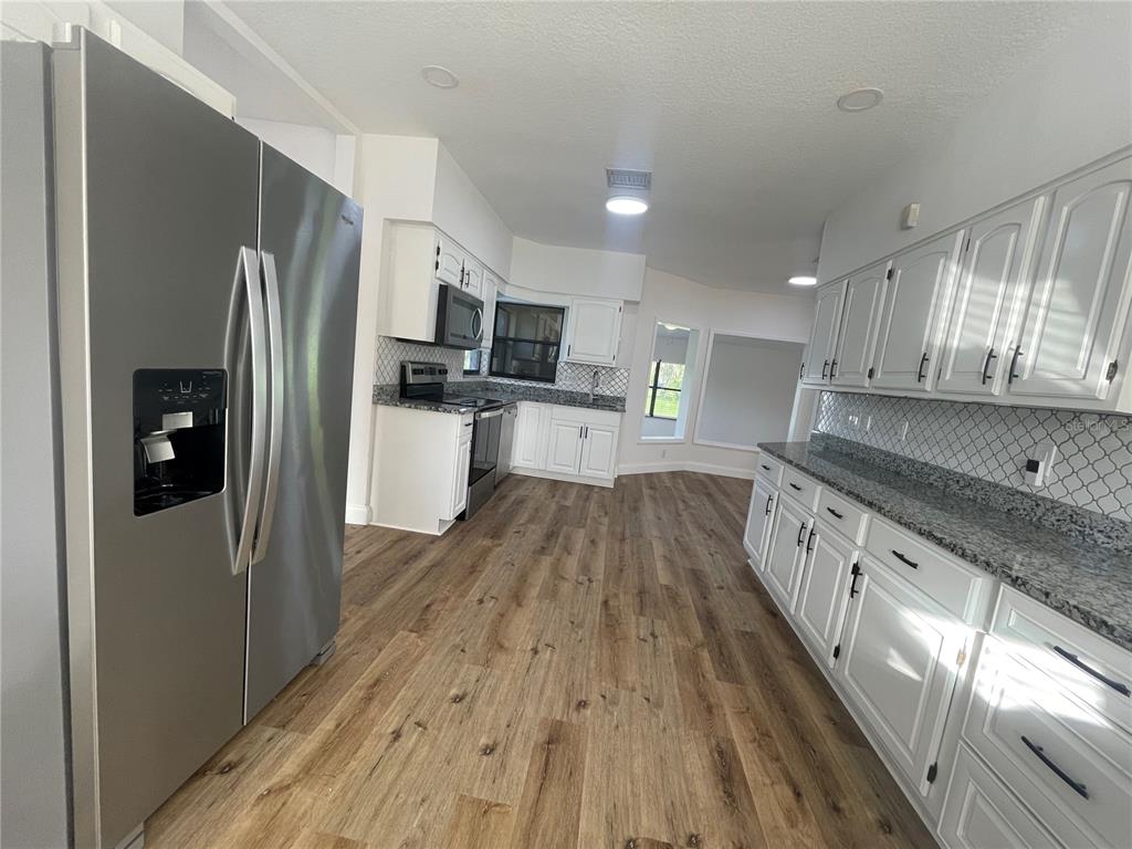 755 South Narcoossee Road St. Cloud, FL 34771 - Photo 12 of 44 a white kitchen with wooden floor and stainless steel appliances