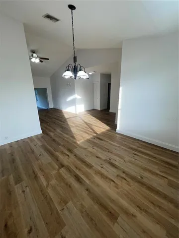 a view of a livingroom with a chandelier fan and wooden floor
