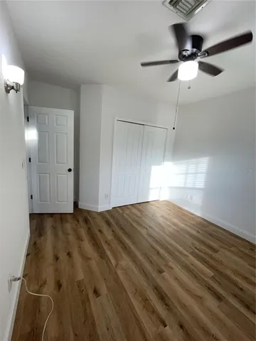 a view of empty room with wooden floor and fan