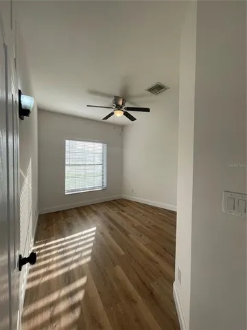 an empty room with wooden floor cabinet and windows