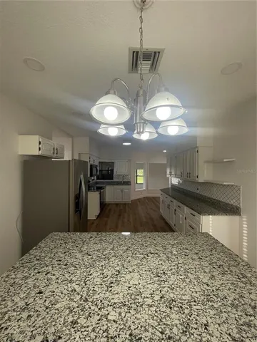 a kitchen with kitchen island granite countertop a sink cabinets and stainless steel appliances