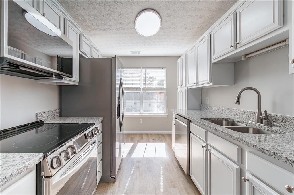 5014 Red Oak Lane Gainesville, GA 30506 - Photo 17 of 43 a kitchen with stainless steel appliances granite countertop a sink a stove and a wooden floors