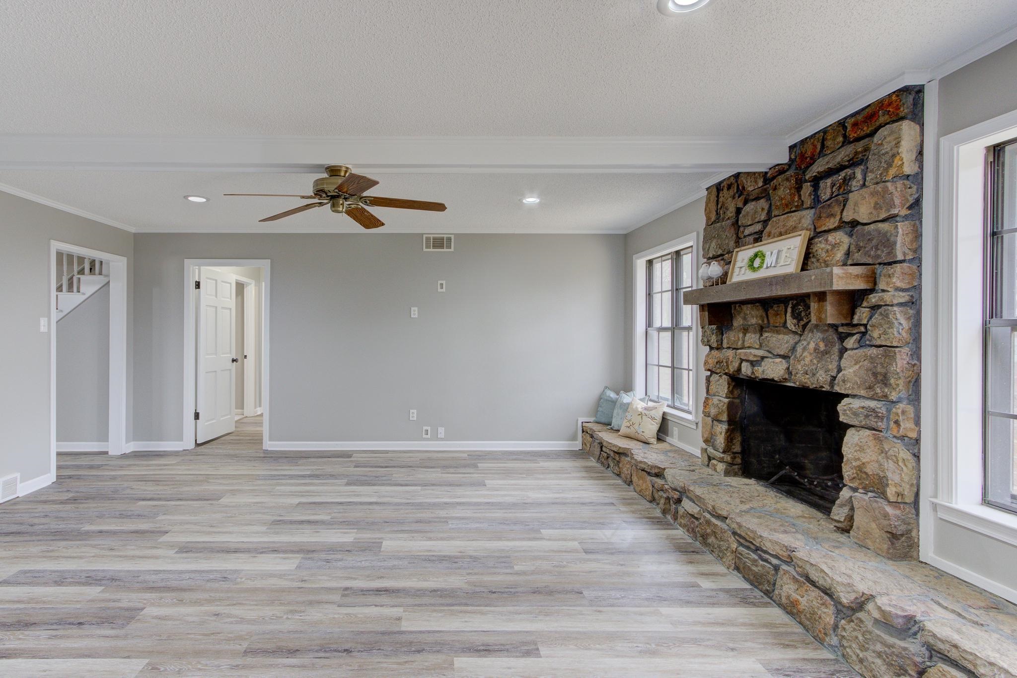 5991 Explorer Road Bartlett, TN 38134 - Photo 20 of 39 Unfurnished living room featuring LVP flooring, wood burning fireplace, and a ceiling fan