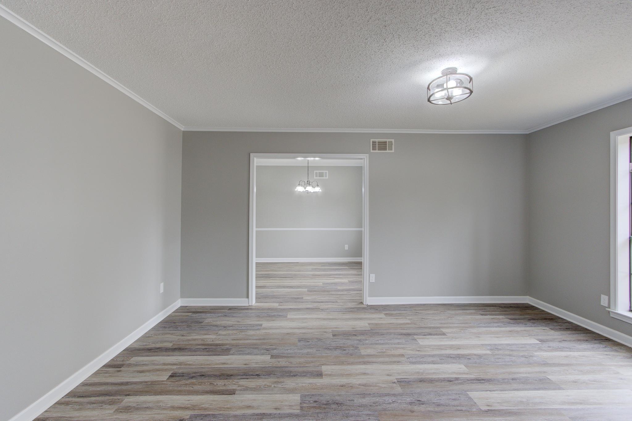 5991 Explorer Road Bartlett, TN 38134 - Photo 7 of 39 Living room entering dining room with an inviting chandelier, baseboards, LVP flooring, and ornamental molding