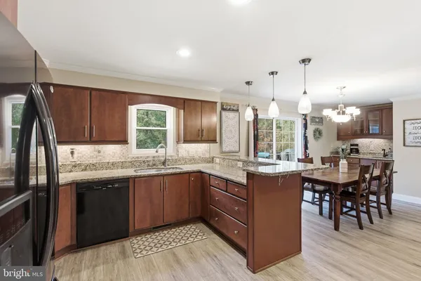 a kitchen with granite countertop a refrigerator a sink dishwasher a oven and a dining table with wooden floor