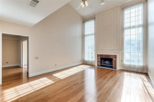 an empty room with wooden floor fireplace and windows