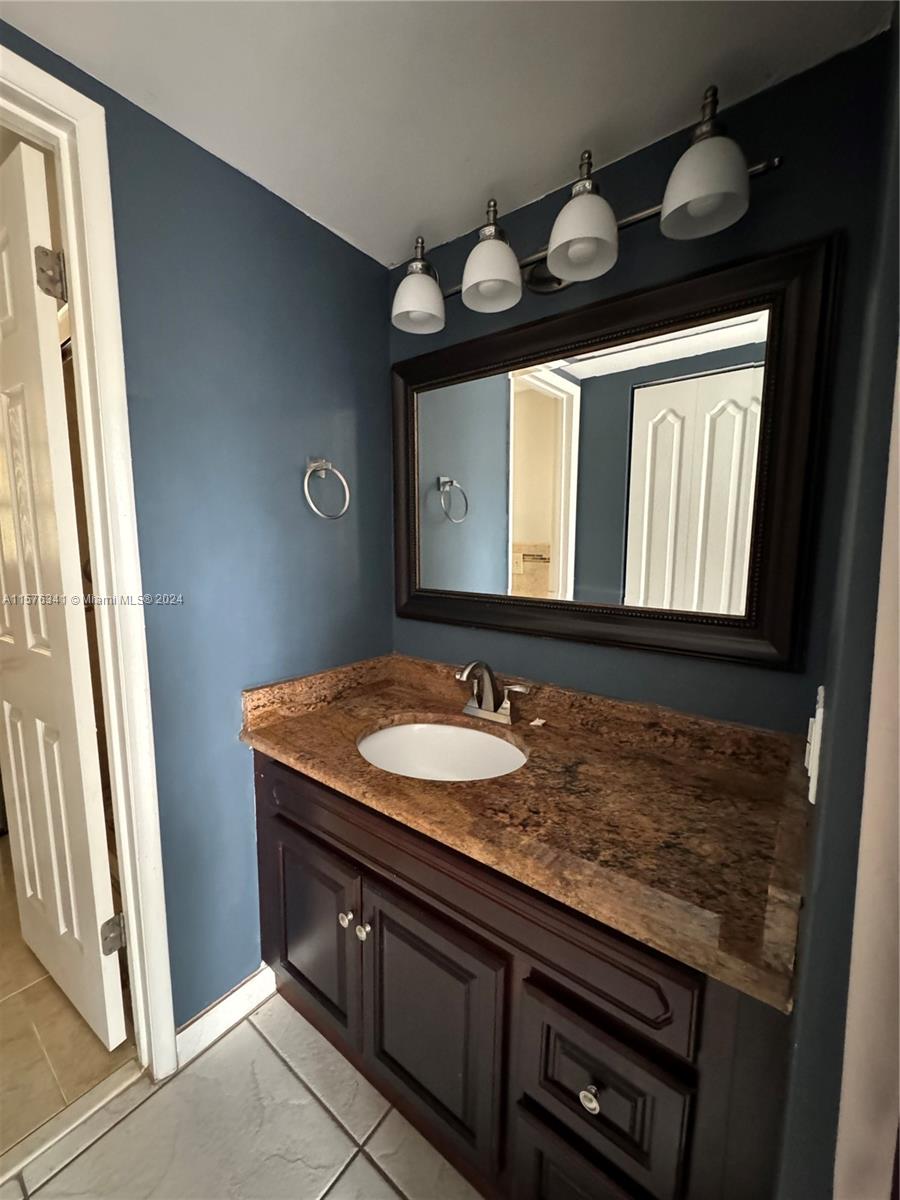 a bathroom with a granite countertop sink a large mirror and a toilet