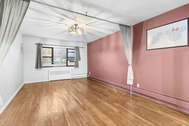 an empty room with wooden floor chandelier and windows