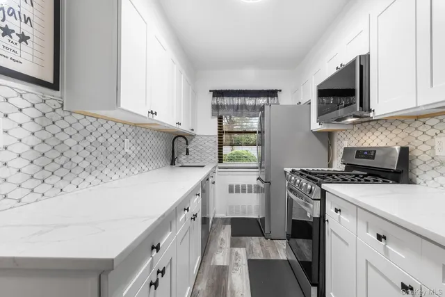 a kitchen with stainless steel appliances a sink stove top oven and white cabinets