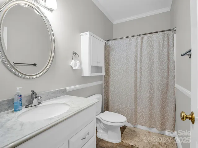 a bathroom with a granite countertop sink vanity mirror and toilet