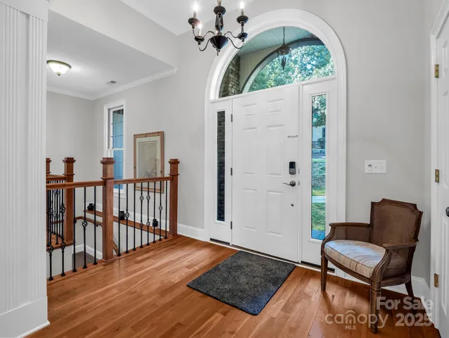 a view of a hallway with wooden floor and a chandelier