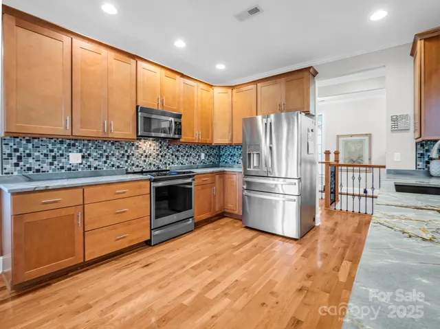 a kitchen with stainless steel appliances granite countertop a refrigerator a stove a sink and a microwave