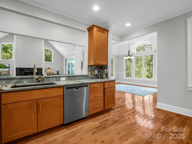 a large kitchen with kitchen island granite countertop wooden floors white cabinets a sink and a window
