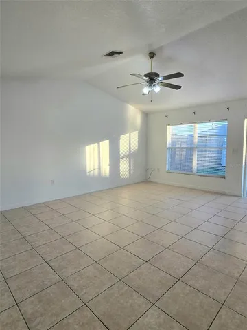 an empty room with windows and fan