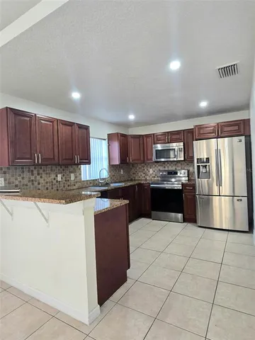 a kitchen with stainless steel appliances granite countertop a refrigerator and a stove top oven