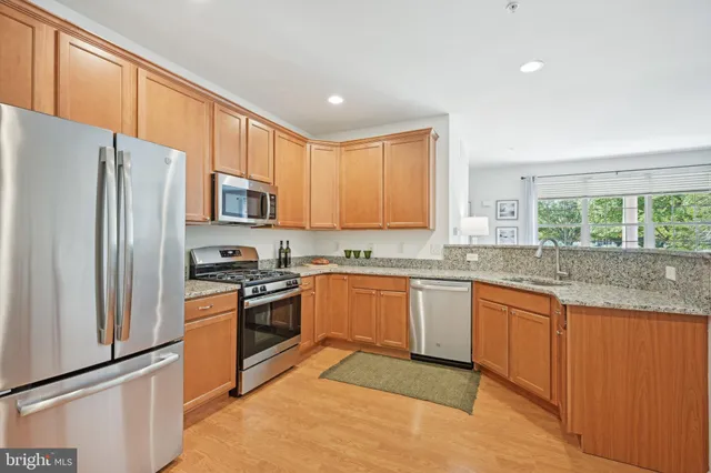 a kitchen with granite countertop stainless steel appliances a refrigerator sink and microwave