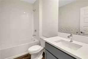 a bathroom with a granite countertop sink a toilet a mirror and bathtub