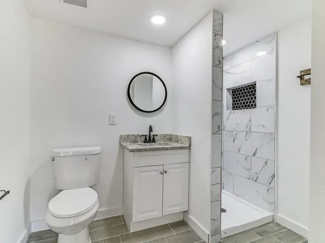 a bathroom with a granite countertop toilet sink mirror and vanity
