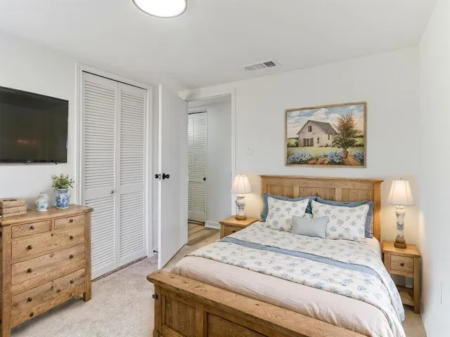 a bedroom with a bed and a flat tv screen on dresser