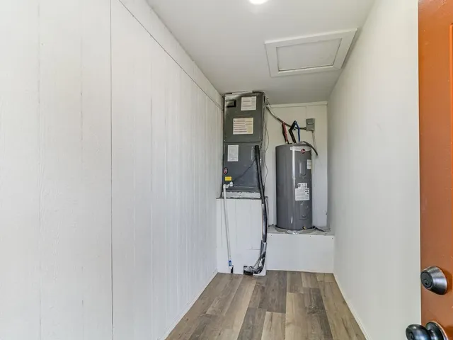 a view of a hallway with wooden floor and a bathroom