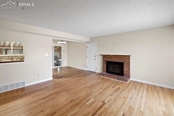 a view of empty room with wooden floor and fireplace