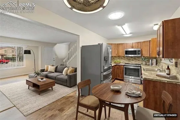 a kitchen with stainless steel appliances granite countertop a refrigerator a stove a sink a dining table and chairs with wooden floor
