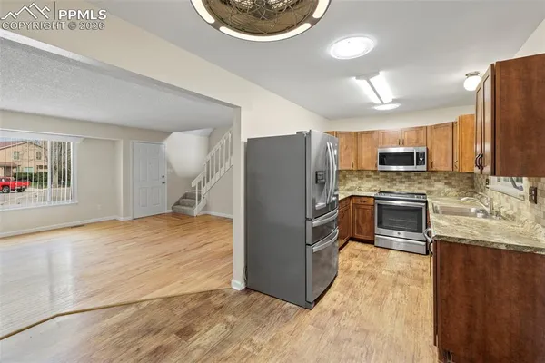 a kitchen with stainless steel appliances granite countertop a refrigerator a stove a sink and a oven