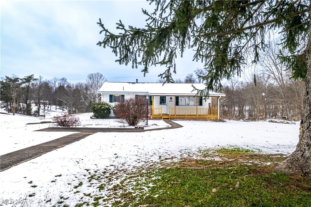 Snow covered rear of property with a wooden deck