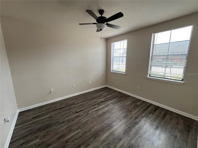 a view of empty room with wooden floor and fan