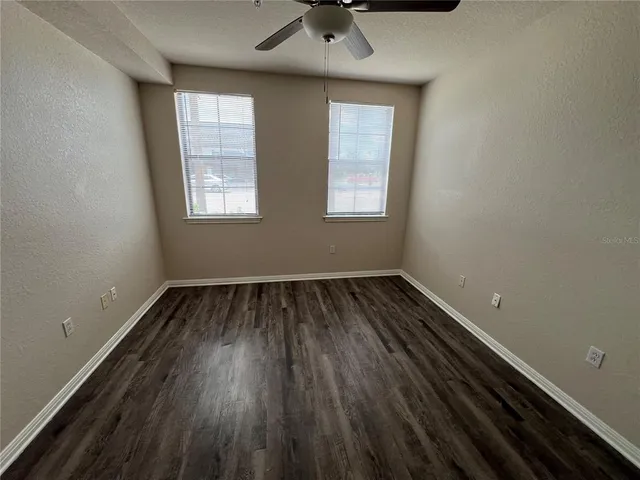 an empty room with a hardwood and windows