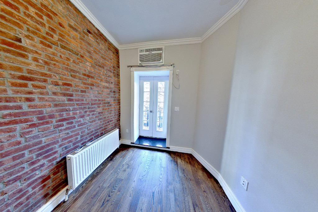 424 West 51st Street, Unit 2 Manhattan, NY 10019 - Photo 7 of 9 a view of an empty room with wooden floor and a window