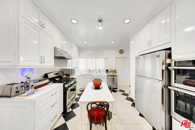 a kitchen with stainless steel appliances a stove a sink a stove a refrigerator and white cabinets with wooden floor