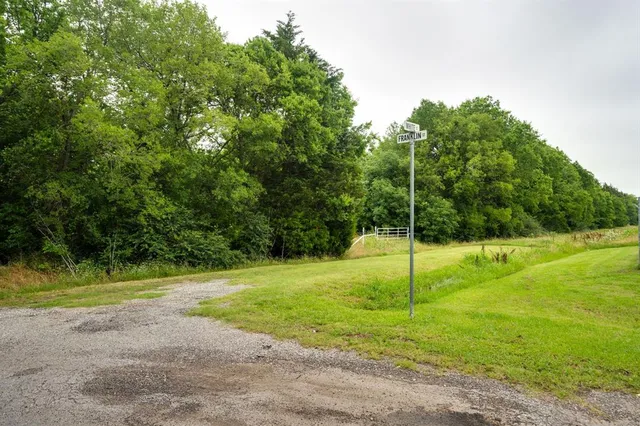 a house is sitting in middle of the green field
