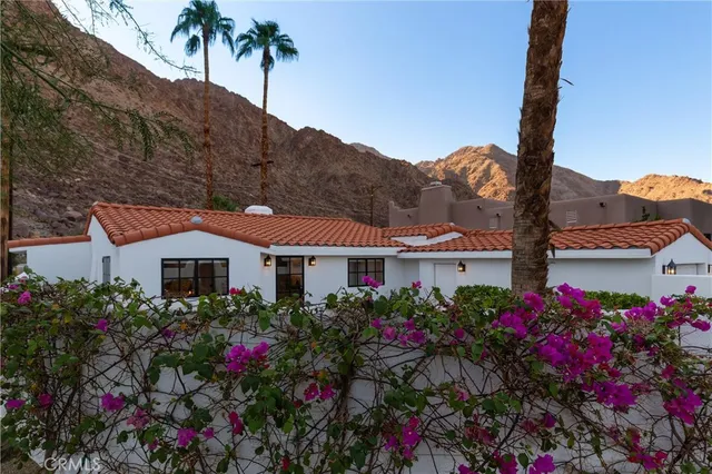 a front view of a house with a big yard and potted plants