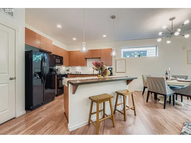 a kitchen with stainless steel appliances granite countertop a stove a sink dishwasher and a refrigerator with wooden cabinets