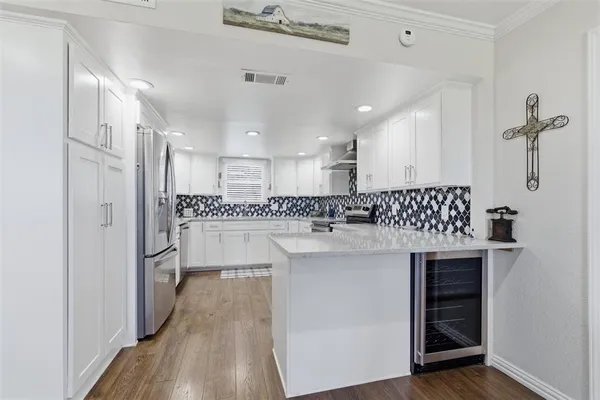 a kitchen with kitchen island white cabinets and stainless steel appliances