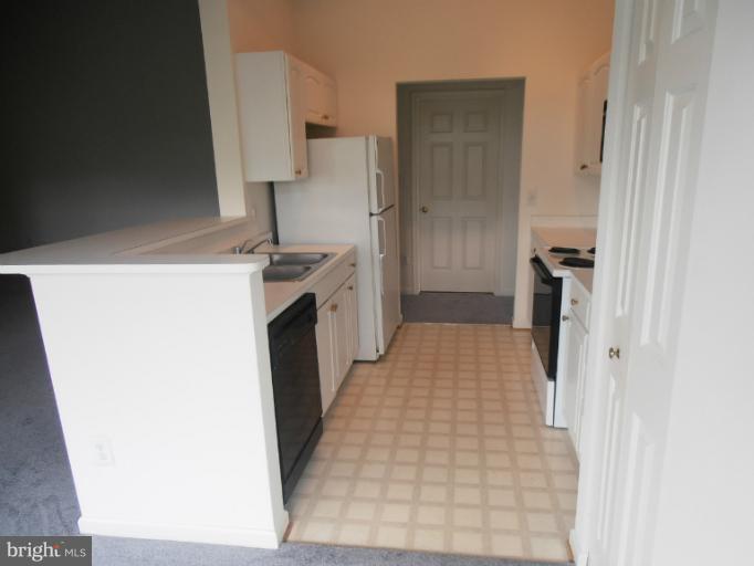 693 Winding Stream Way, Unit 302 Odenton, MD 21113 - Photo 14 of 26 a hallway with a white stove top oven and refrigerator