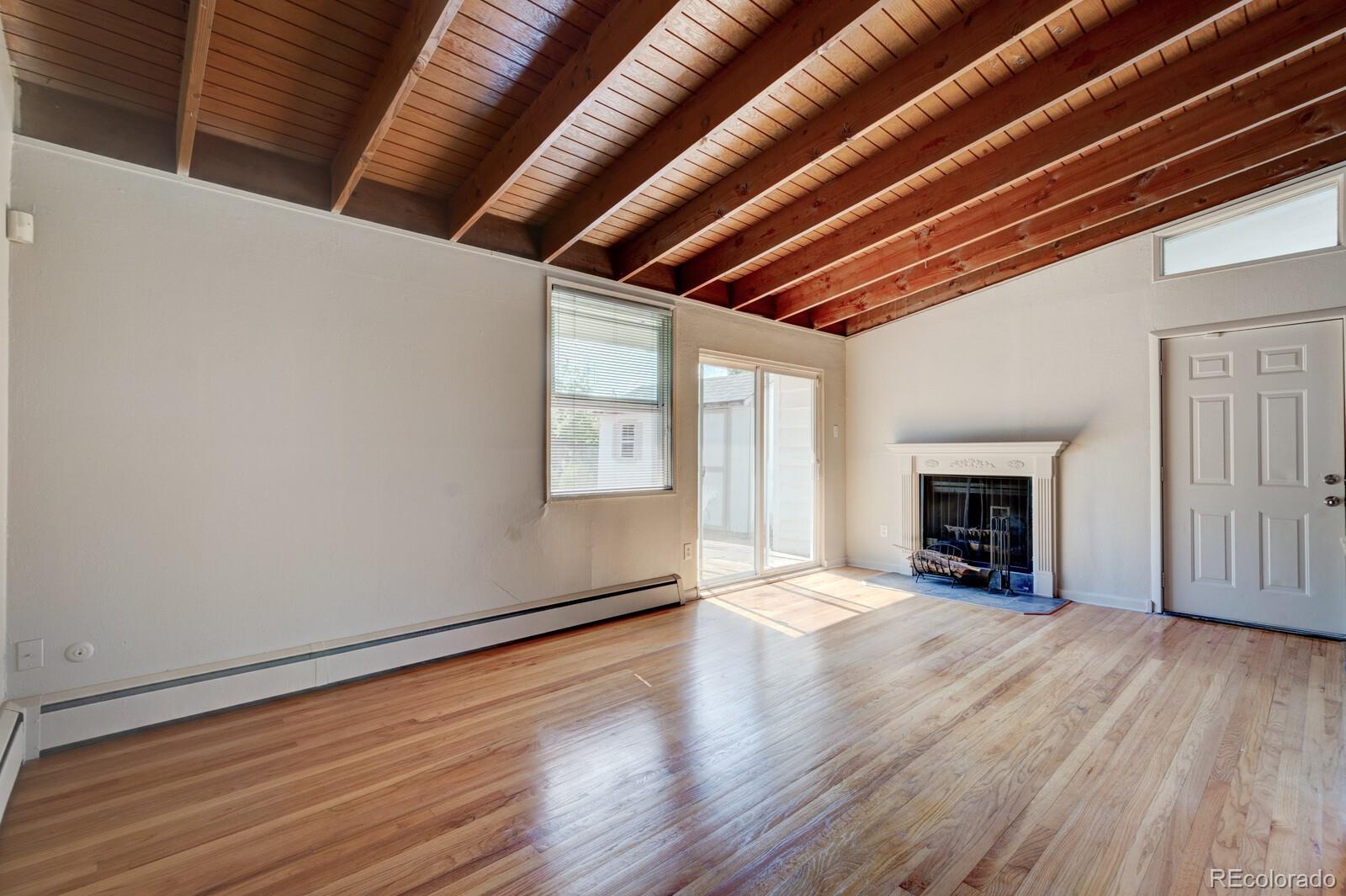 7928 Raleigh Place Westminster, CO 80030 - Photo 4 of 24 a view of an empty room with wooden floor fireplace and a window