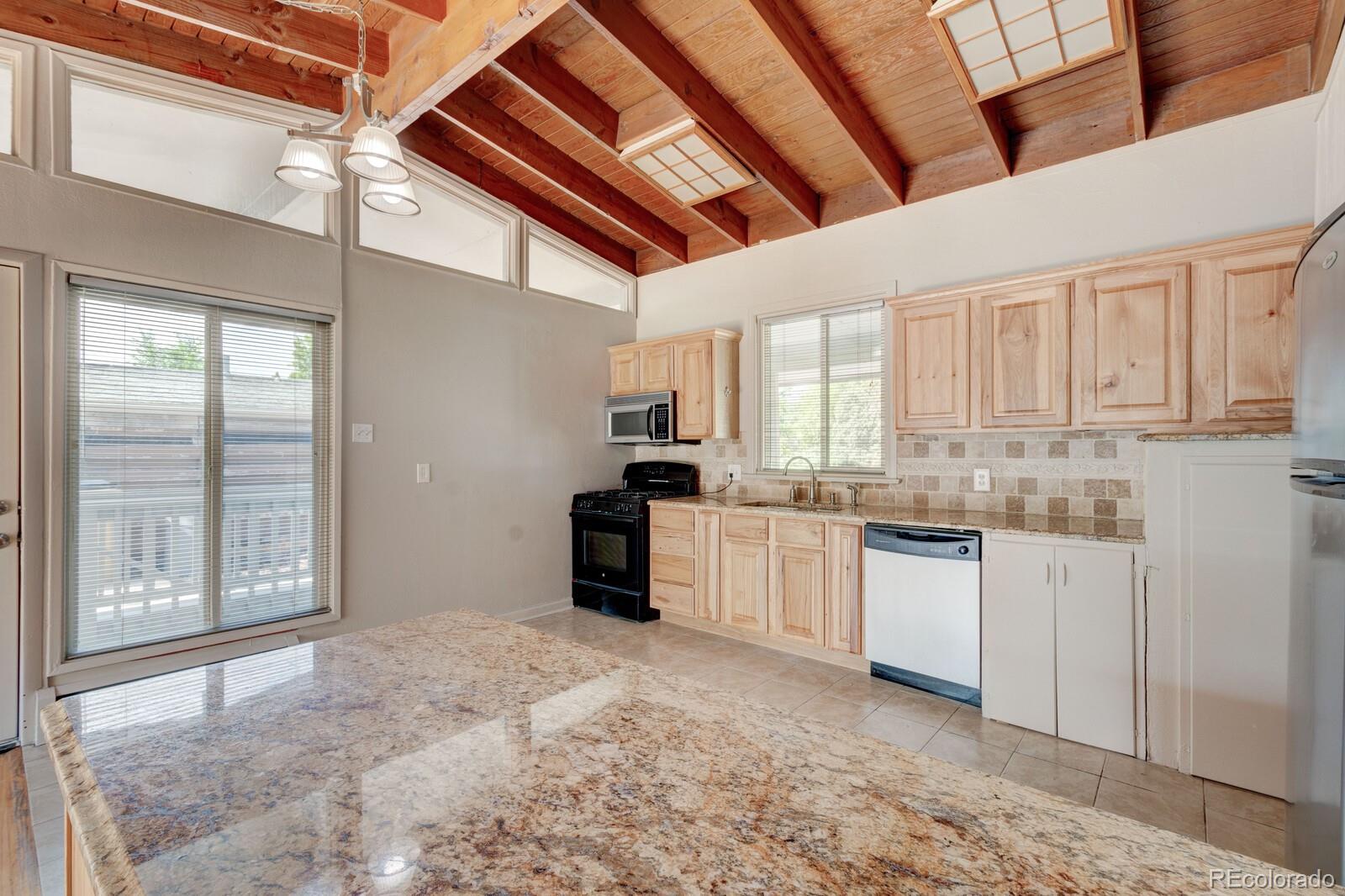 7928 Raleigh Place Westminster, CO 80030 - Photo 8 of 24 a large white kitchen with granite countertop a stove a sink and a refrigerator