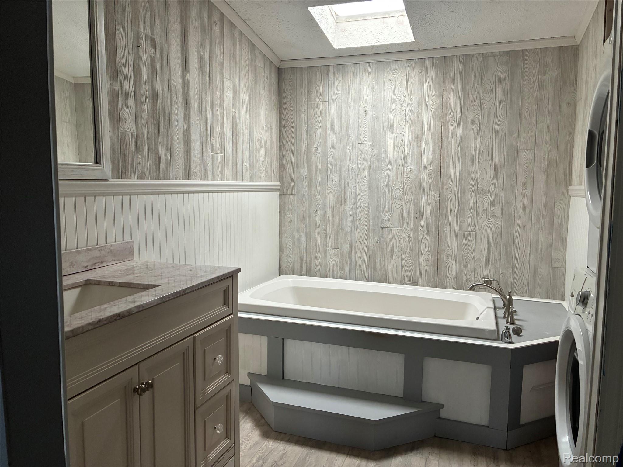 7364 Kings Court Alma, MI 48801 - Photo 8 of 16 Bathroom featuring a built-in tub, skylight, and wood-finish wall paneling
