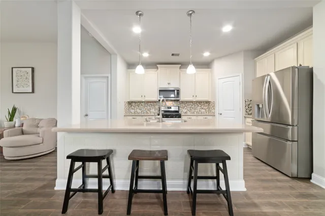 a kitchen with stainless steel appliances granite countertop a table chairs refrigerator and microwave