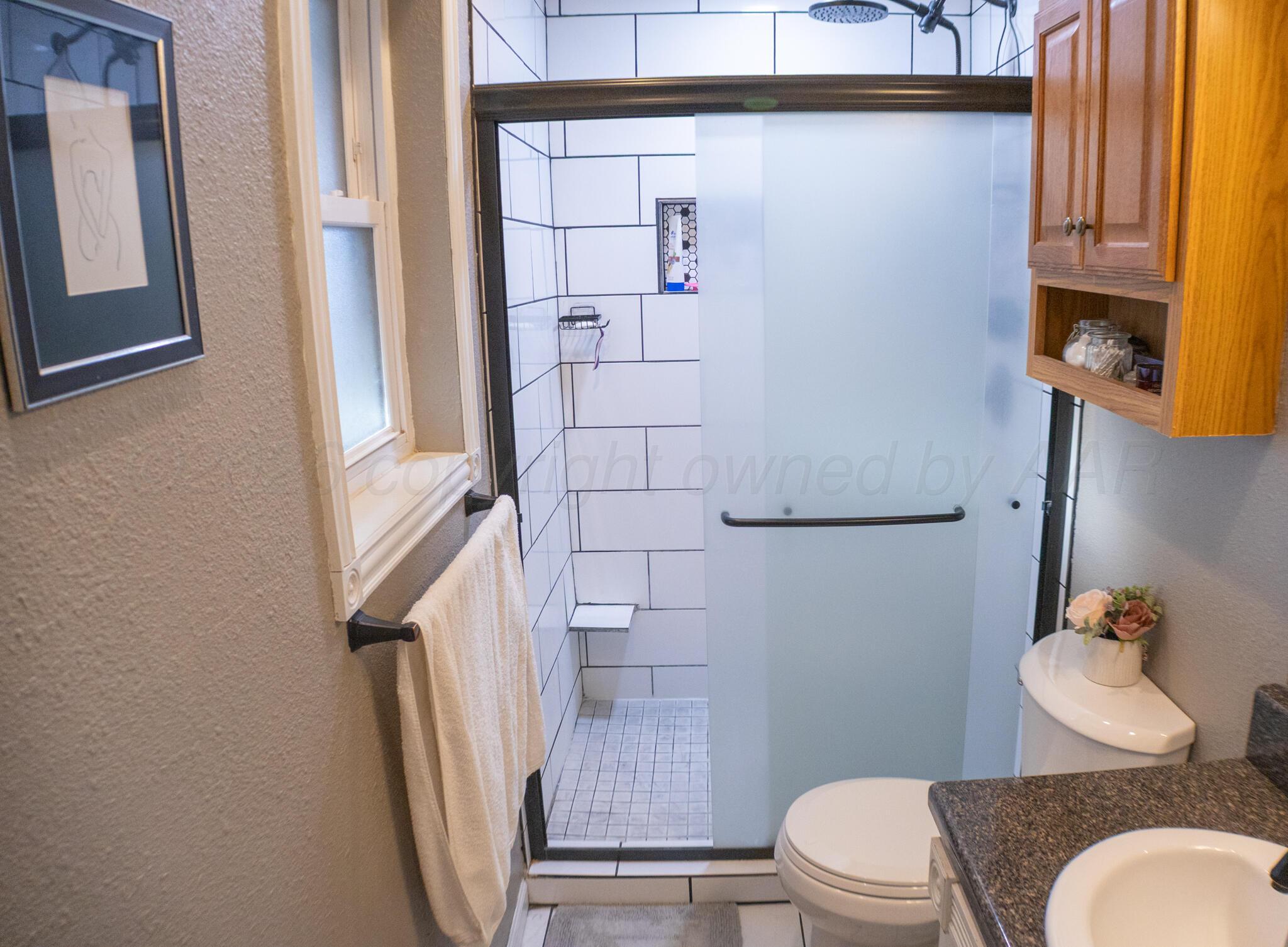 4504 Goodnight Trail Amarillo, TX 79109 - Photo 18 of 32 a white toilet sitting next to a bathroom sink and a mirror